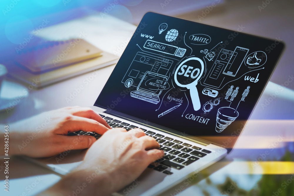 Businessman hands working on laptop at office workspace to discover search engine optimization to succeed in start up. SEO icons sketch on glass screen.