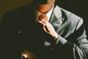 Polícia prende suspeitos de golpe do falso advogado e fraude digital em processos judiciais 1 | Juristas A man in a black suit loosening his tie