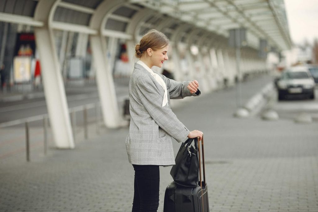 Modelo de petição de ação de reparação a título de danos morais e materiais por cancelamento indevido de transfer de aeroporto ao hotel 2 | Juristas Cheerful female manager checking time on wristwatch standing with bags near bus station