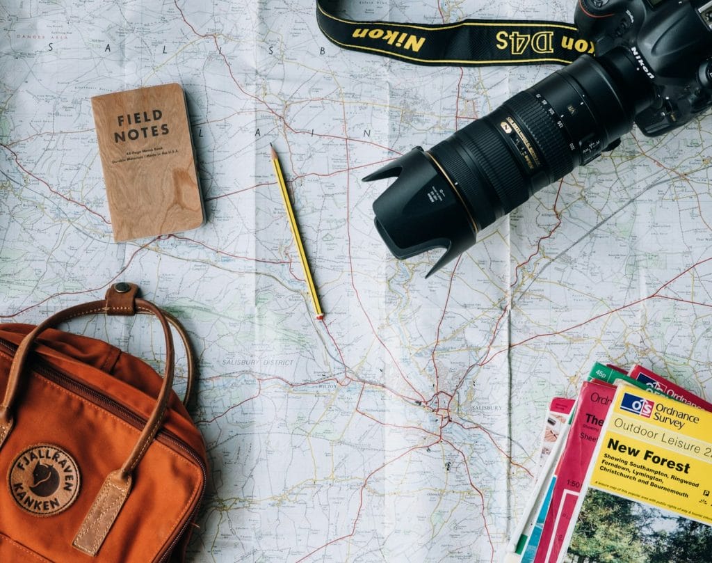 Modelo de petição de ação de reparação a título de danos morais e materiais por cancelamento Indevido de pacote de viagem 2 | Juristas flat lay photography of camera, book, and bag